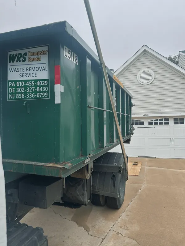 WRS roll off dumpster being set on wood boards in a residential driveway