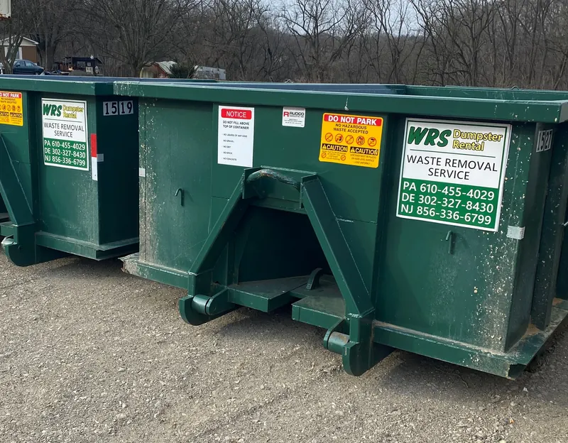 Green WRS roll off dumpsters with loading and safety notices on the side